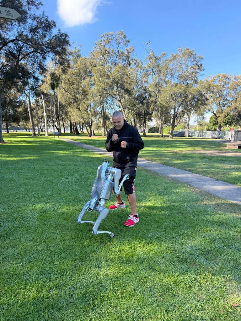 Anthony Mundine with a quadruped robot in boxing stance